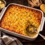 Golden corn casserole in a square baking dish with a scoop taken out