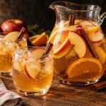 Pitcher of sparkling apple cider punch with apple and orange slices and cinnamon sticks
